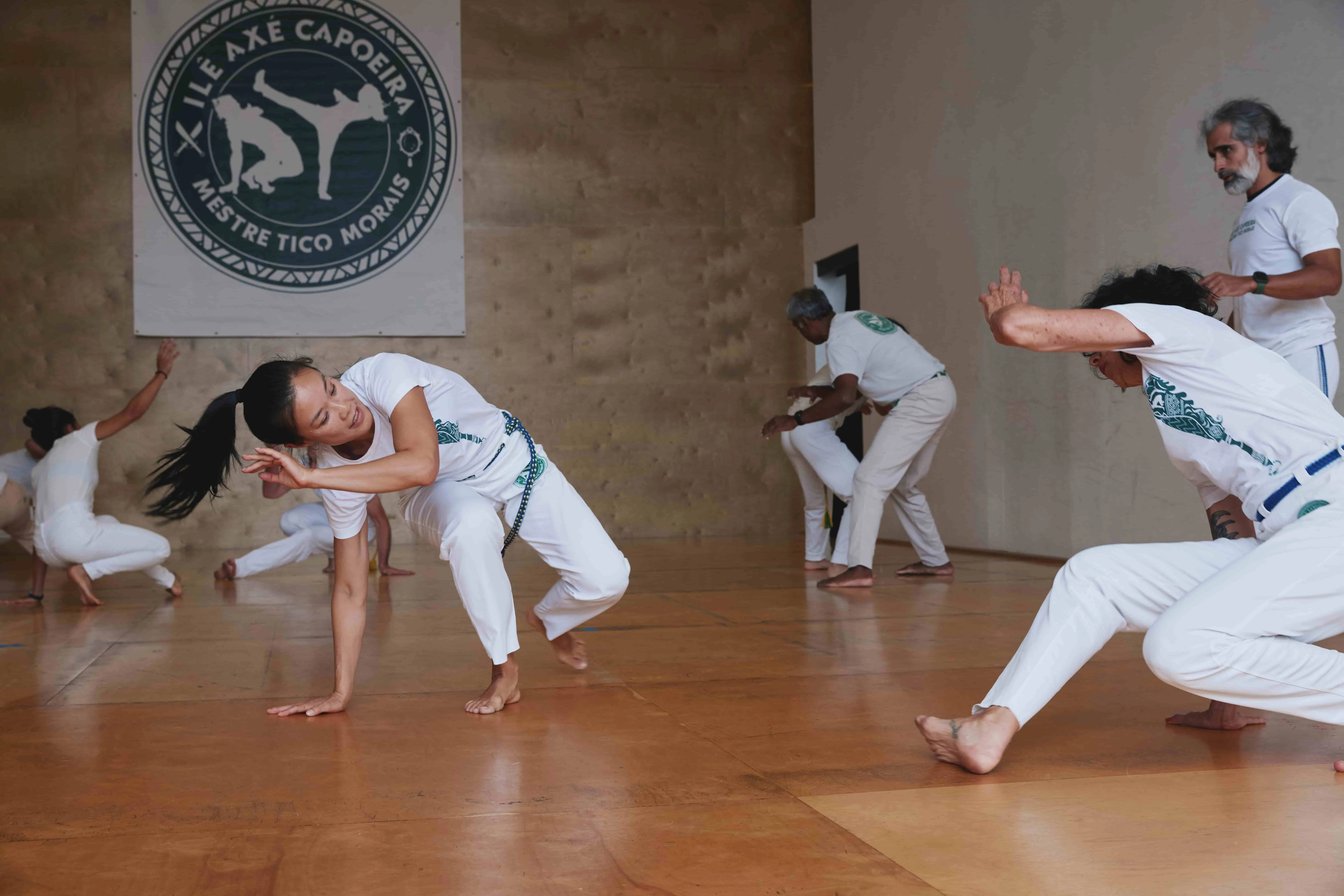 Students practice capoeira movements with partners with guidance from the instructor, Mestre Tico.